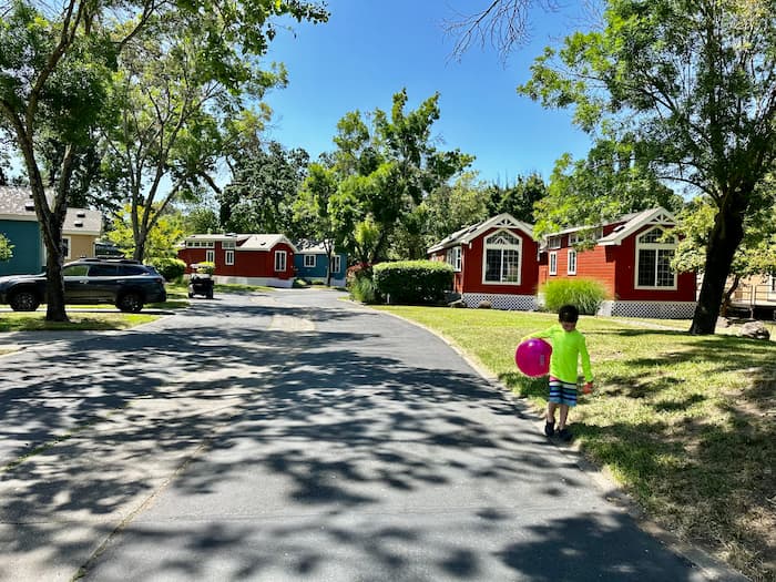 child walking with big ball with tiny homes in background