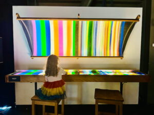 child sitting at rainbow light exhibit