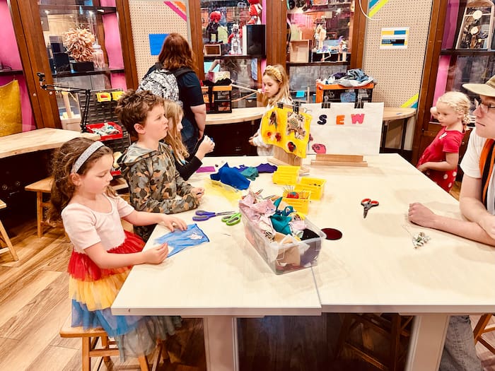 little kids sitting at table sewing