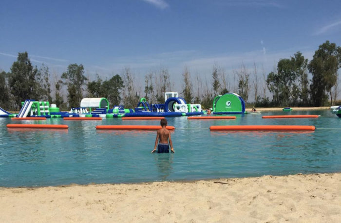 child in water with beach and inflatable water sports obstacle course