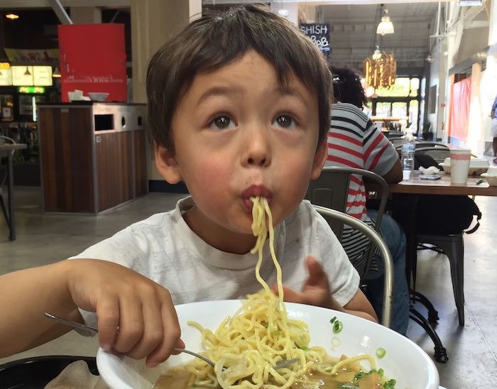 Child slurping ramen noodles