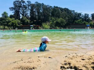 little girl laying in shallow water of lake