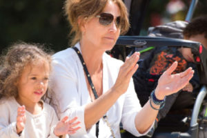 girl and woman clapping, baby in stroller asleep