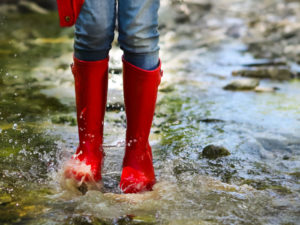Child in red rainboots playing in the rain