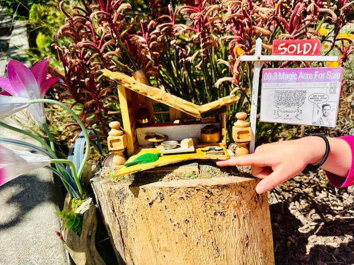 little kid hand pointing at fairy house door