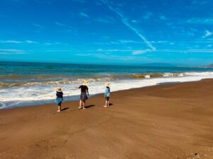three kids on beach by water's edge