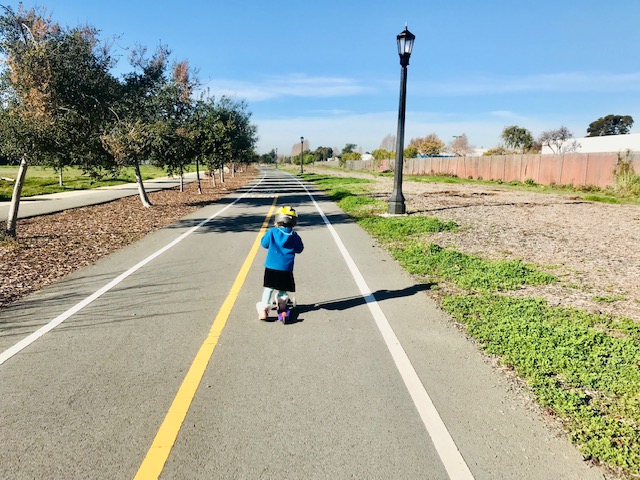 child on scooter on bike path