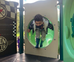 kid playing in dimond park tot lot spin racer