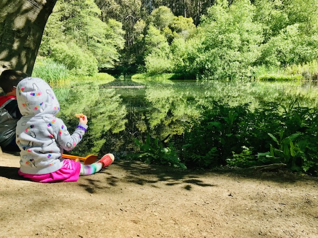 child sitting next to lake