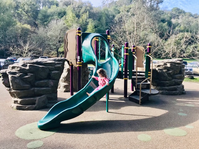 child going down slide at playground