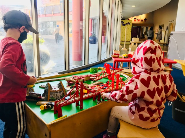two children playing at train table