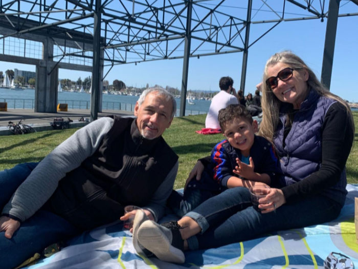 grandparents and grandchild eat on blanket