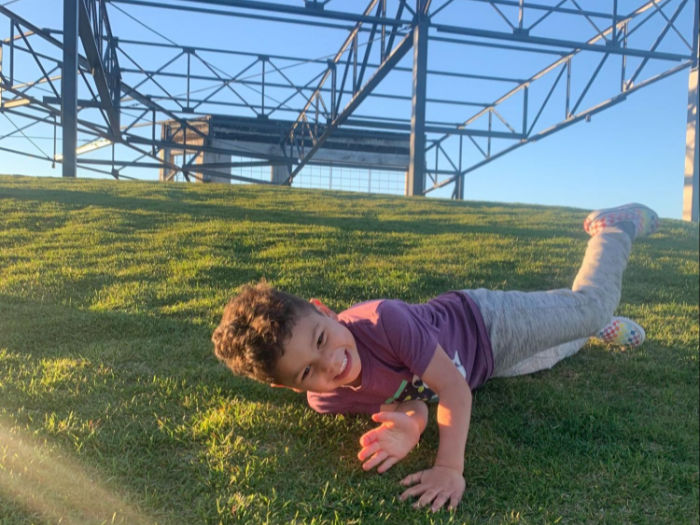 child rolling down grassy hill