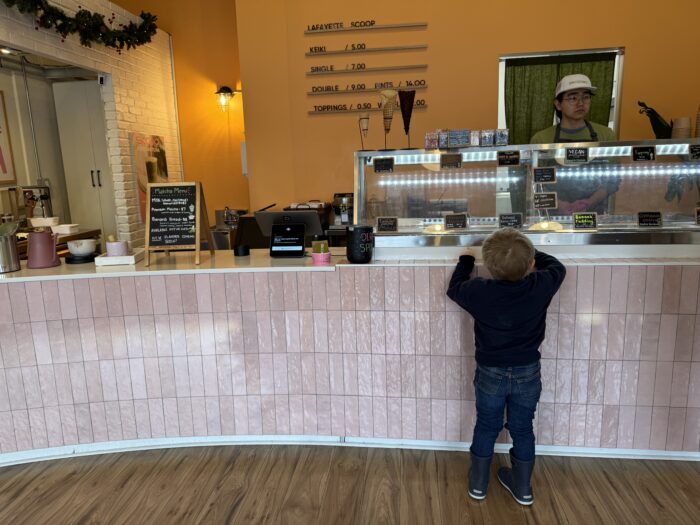 Child at Scoop ice cream shop looking over counter.