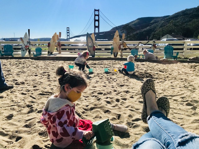 child playing in sand Golden Gate Bridge behind