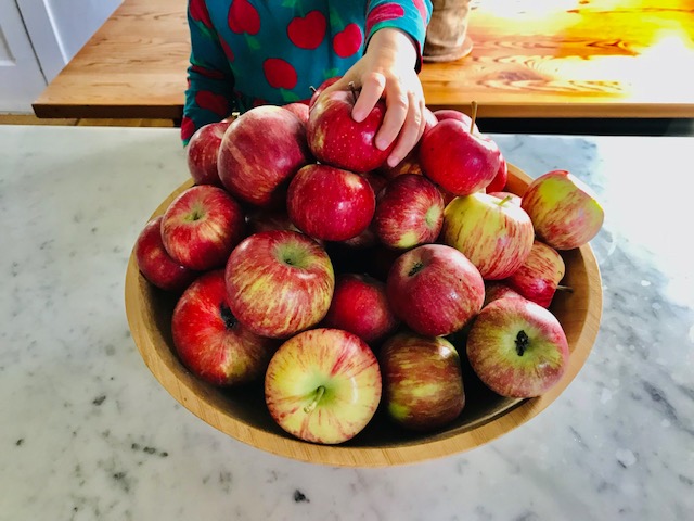 bowl of apples with child's hand
