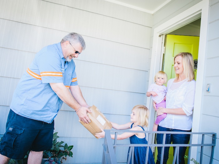 person delivering diaper supplies to a family with two kids and a parent.
