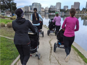four people pushing strollers from behind