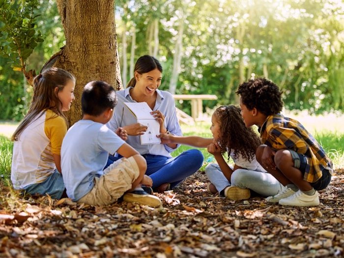 four kids reading with an adult in the outdoors as a small group tutoring session