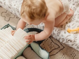 baby reaching for a stack of diapers