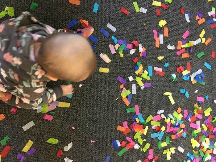 Baby crawling through confetti at New Year's Eve celebration