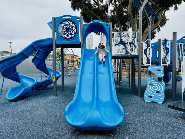 child going down blue slide