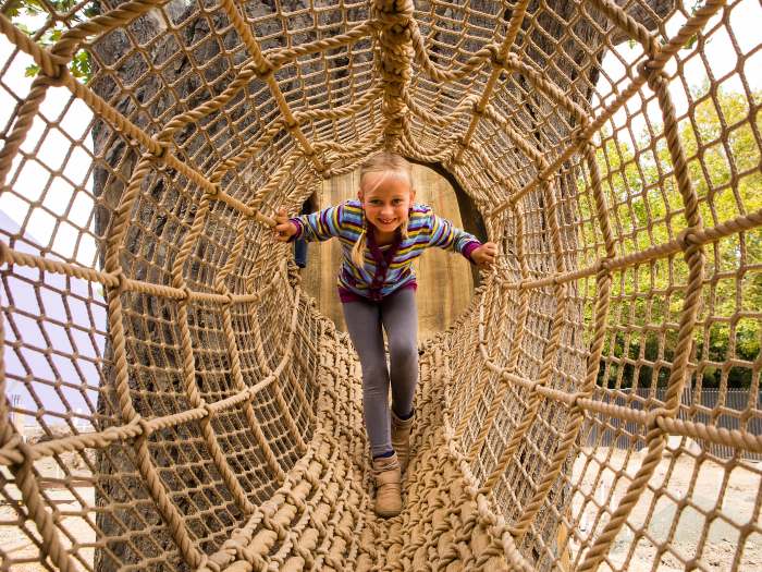 Kid crawling through the Tree Climber at the Bill's Backyard exhibit at the San Jose Discovery Museum