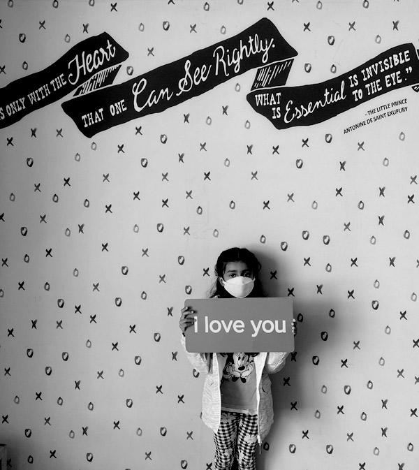 black and white photo of child holding up LOVE you sign