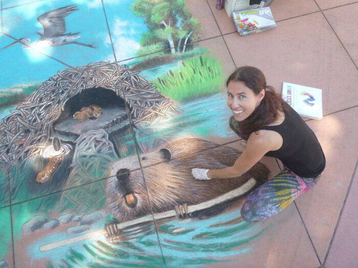 Woman drawing chalk art of beaver