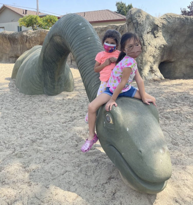 Dinosaur play structure with two girls on top