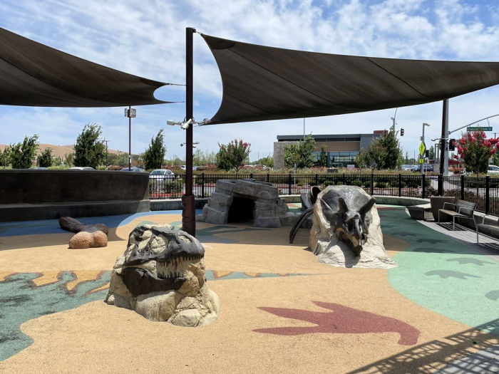 shaded play area with dinosaur climbers
