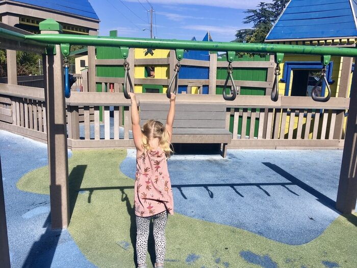 Child hangs on monkey bars at all-abilities playground