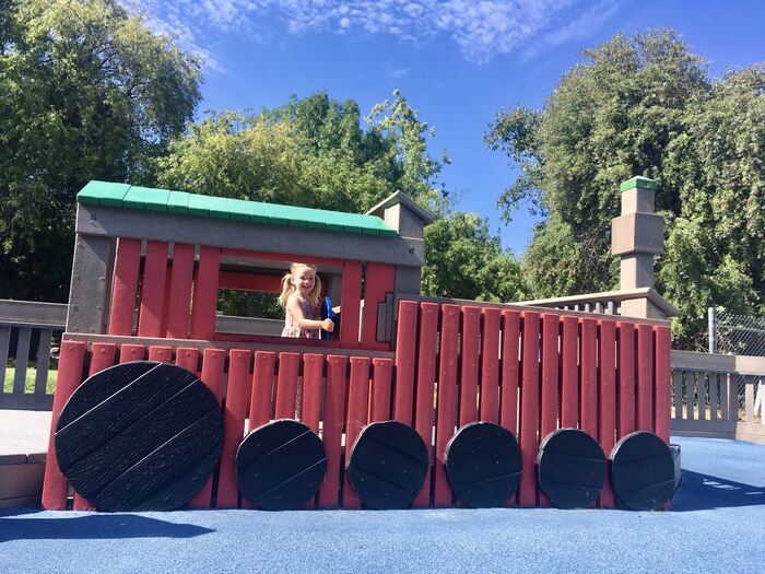 Child pretends to drive at train-themed play structure