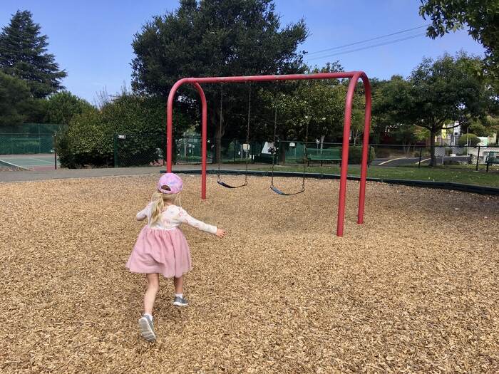 Child runs to swing set at playground
