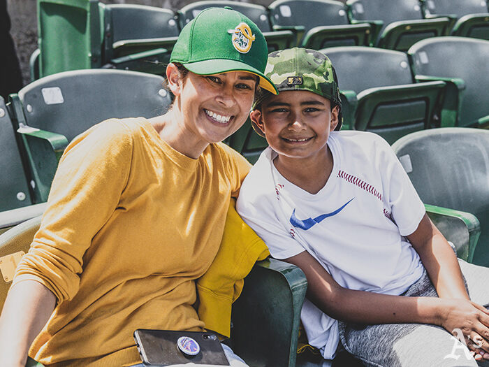 Mother and son at baseball game wearing Oakland A's hats