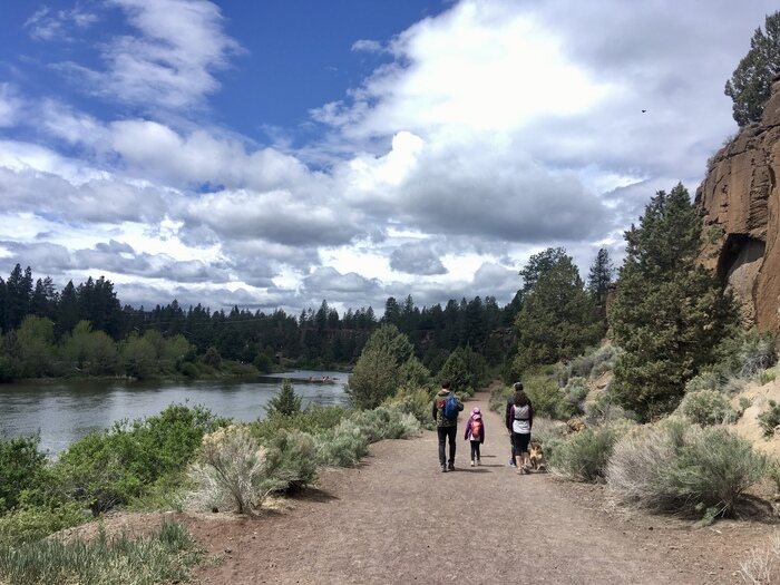 Family hikes in high desert trail along river in Bend Oregon