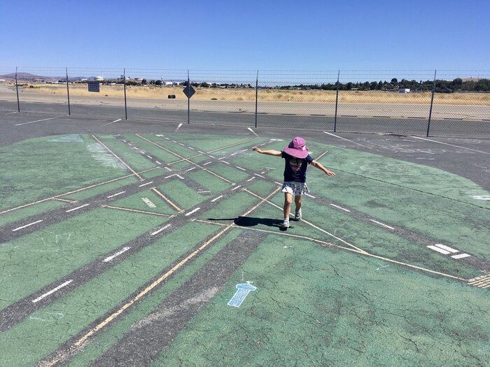 Child runs down painted runway on ground.