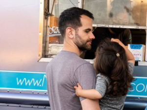 Father and child order meal from food truck