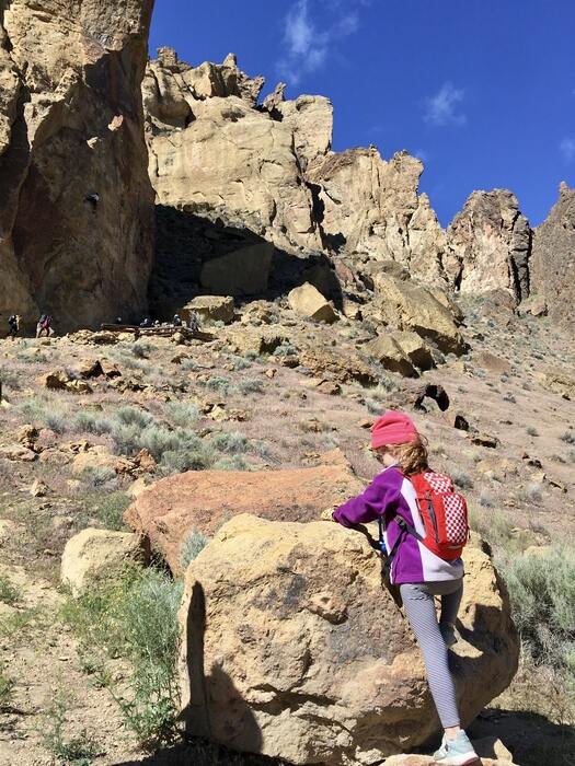 Child scrambles up rock near canyon.