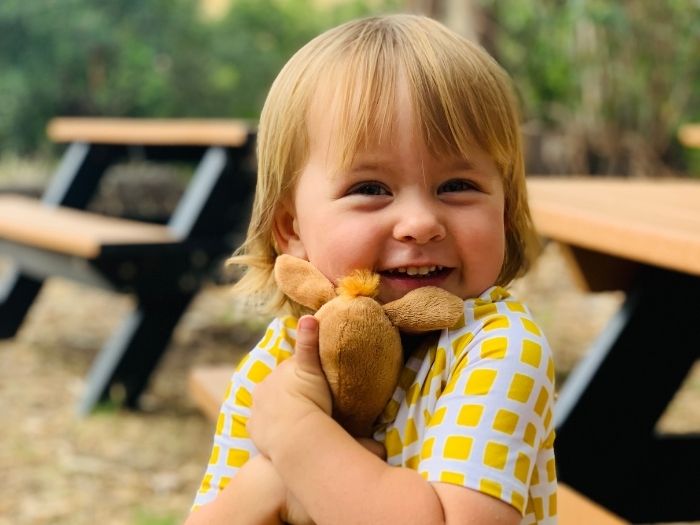child hugging a stuffie on a picnic table