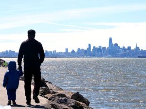 kid and adult walking along sf bay