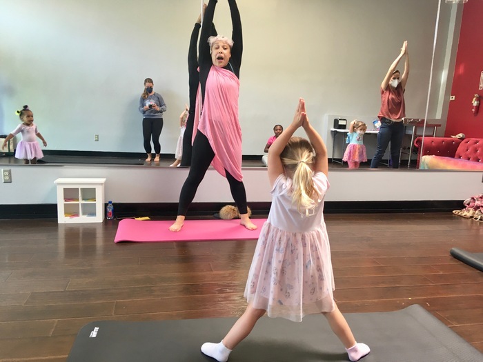 Child in yoga pose with instructor