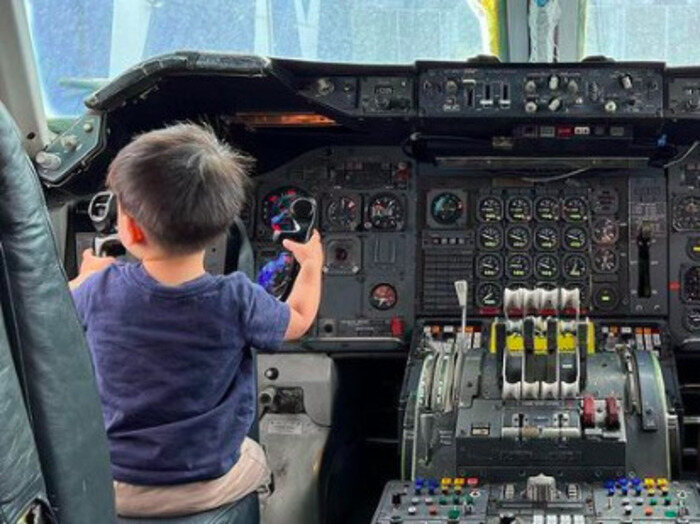 Child sits in pilot seat at Hiller Aviation Museum