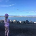 Child watching plane while visiting waterfront park