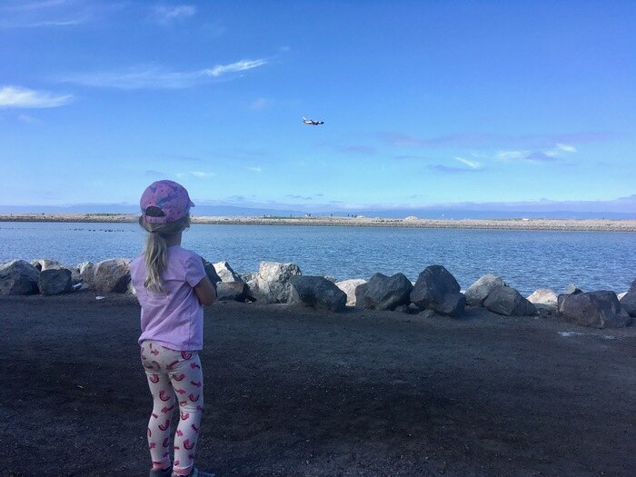 Child watching plane while visiting waterfront park