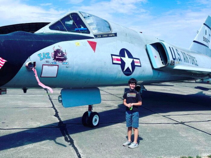 Child stands next to fighter jet