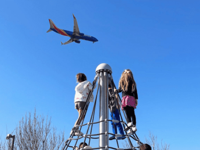 Children climbing on play structure watch plane fly overhead