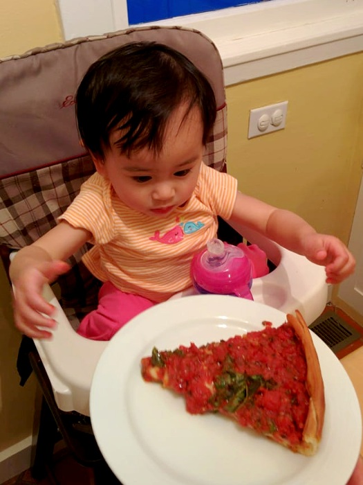 Baby eating a slice of Zachary's chicago style pizza at home