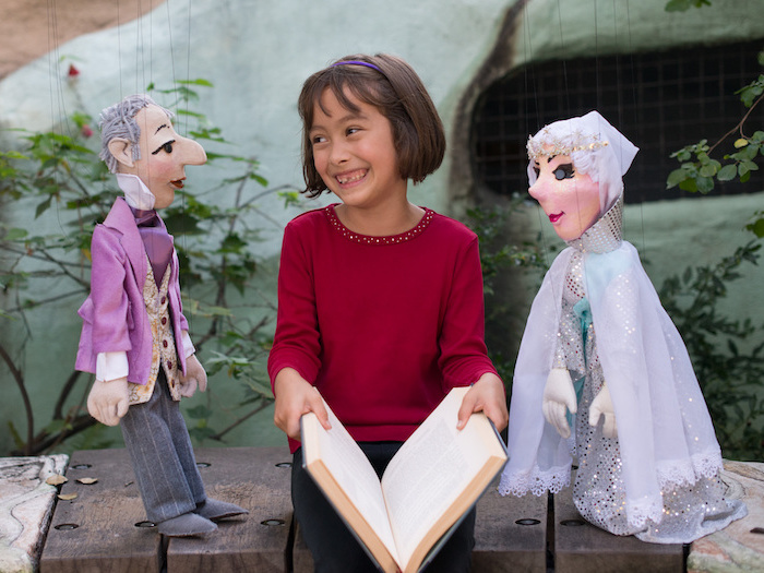 child with marionette puppets and a book