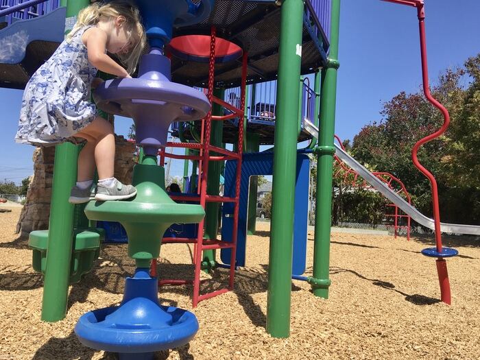 Child on climbing feature at playground in Richmond